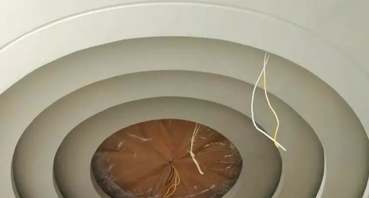 Round gypsum ceiling built in stepped rings around a central wood panel
