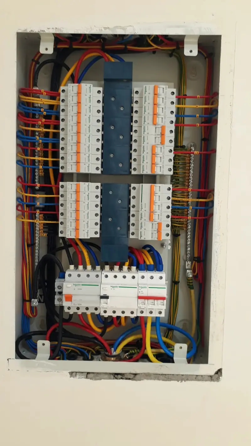 Open distribution board with neatly dressed, colour-coded cables and breakers